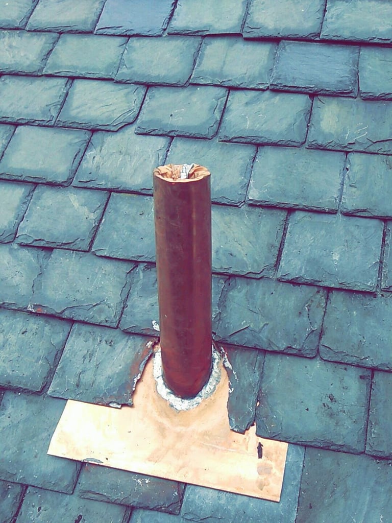 New copper vent pipe and flashing set into a slate roof
