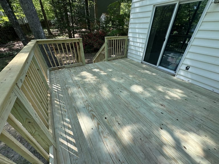 New wooden deck replacement with railings and glass doors overlooking a wooded area, Richmond VA area