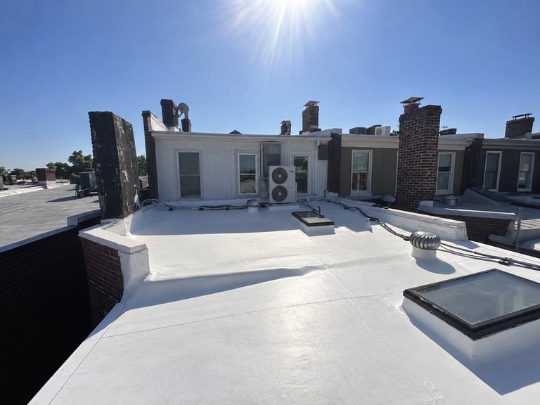 Rooftop with white surface, HVAC units, brick chimneys, and solar panels under clear blue sky