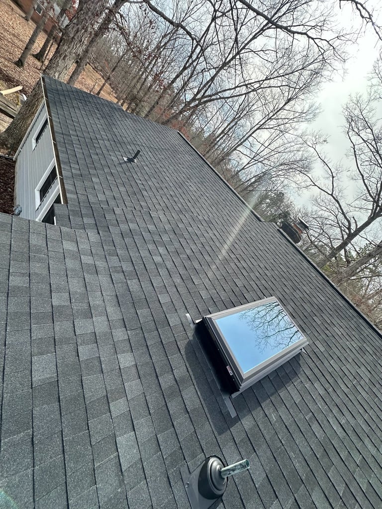Skylight on a dark shingle roof, viewed down the roof slope
