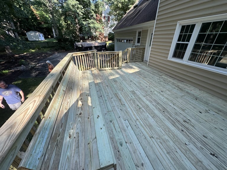 Weathered wooden deck with white railings attached to a beige house, Richmond VA area